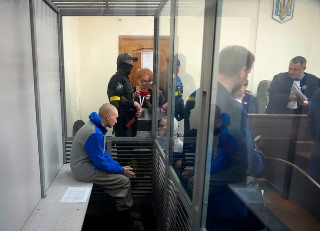 Russian Army Sergeant Vadim Shishmarin, 21, is seen behind a glass during a court hearing in Kyiv, Ukraine, Friday, May 13, 2022. The trial of a Russian soldier accused of killing a Ukrainian civilian began Friday, the first war crimes trial since Moscow's invasion of its neighbor.