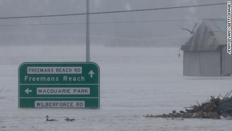 Road signs are seen submerged under flood waters along the Hawkesbury River in the suburb of Windsor, on July 4, 2022.