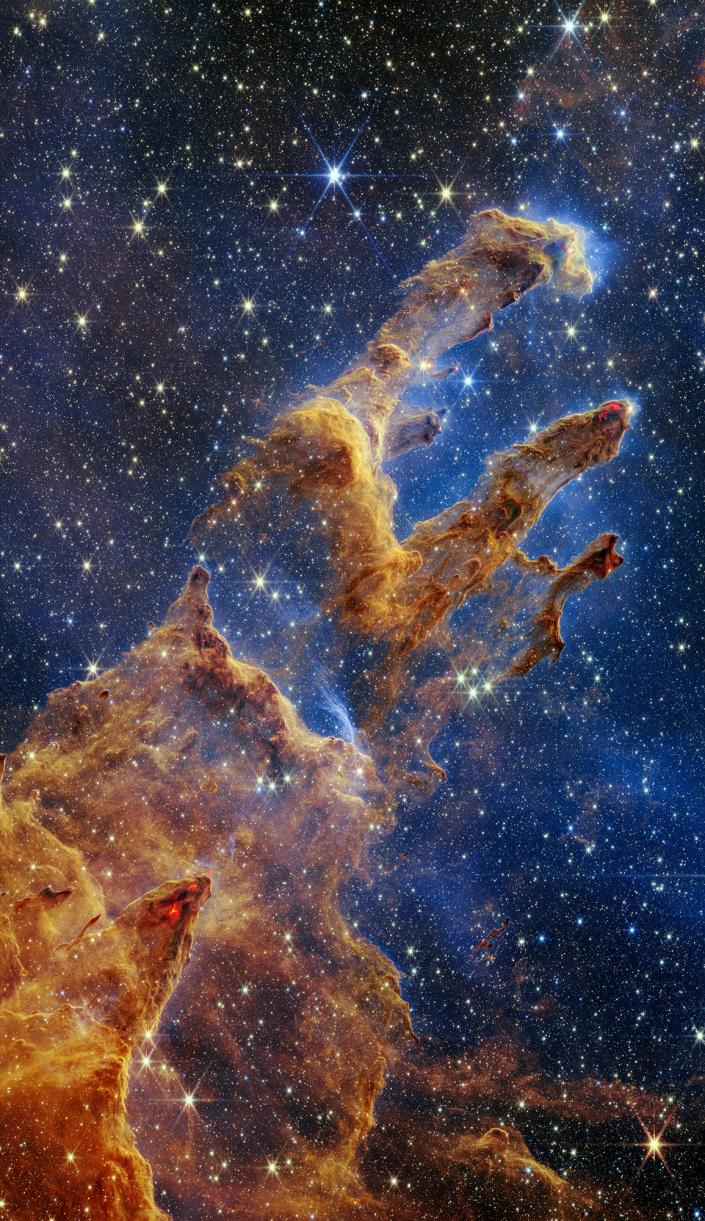 The Pillars of Creation are laid out in a kaleidoscope of color in NASA's James Webb Space Telescope's near-infrared light show.  The pillars look like arches and spiers rising from the desert landscape, but they are filled with translucent gas and dust, and are constantly changing.  This is a region where young stars are forming -- or just barely bursting from their dusty cocoons as they continue to form.