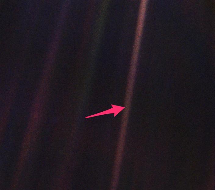 Image of a pale blue dot with an arrow pointing to the ground