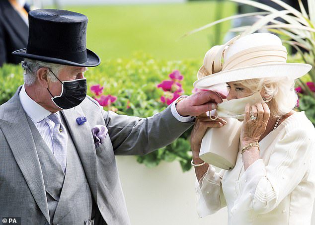 Supportive husband!  King Charles chose a somewhat unusual image for his Christmas card last year, featuring him and the Queen now at Royal Ascot.  The photo shows Charles helping his wife put her face mask on, a nod to the Covid pandemic