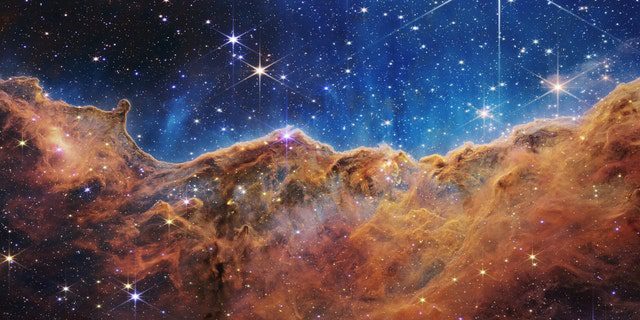 What looks a lot like rocky mountains on a moonlit evening is actually the edge of the nearby, young star-forming region NGC 3324 in the Carina Nebula.  Taken in infrared light by the Near Infrared Camera (NIRCam) on NASA's James Webb Space Telescope, this image reveals previously obscured regions of star birth.